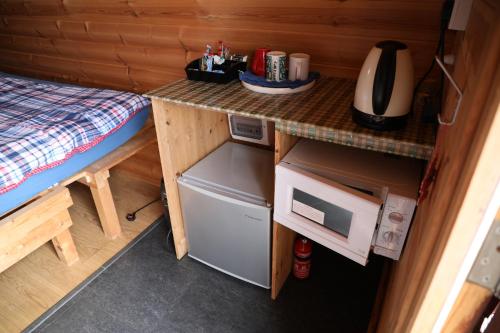 a small kitchen with a table and a small refrigerator at Clovullin Croftview Pod in Ardgour