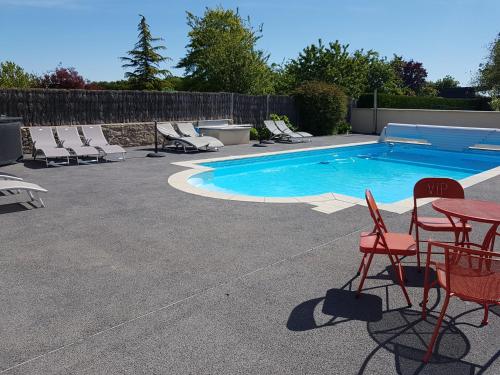 - une piscine avec des chaises et une table à côté dans l'établissement Gite - Studios Marie Barrault, aux Herbiers