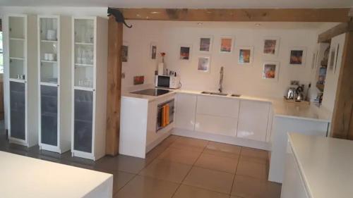uma cozinha com armários brancos e um forno com placa de fogão em Prestwick House - Sleeps 10+ - Main House & 3 Separate Oak Framed Barn Studios - Rural em Chiddingfold