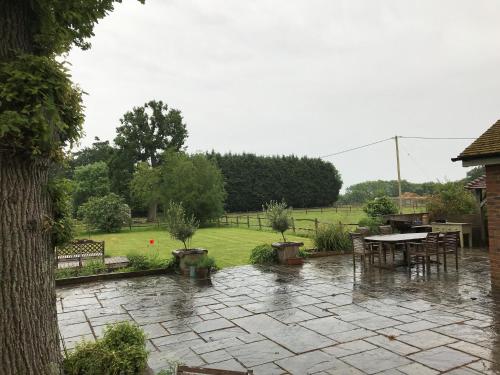 a patio in the rain with a table and chairs at Prestwick House - Sleeps 10+ - Main House & 3 Separate Oak Framed Barn Studios - Rural in Chiddingfold
