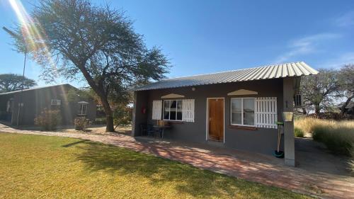 a small house in a yard with a tree at Out Of Nature Country Lodge in Windhoek