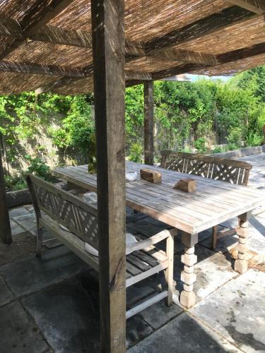 a wooden table and bench under a wooden roof at Prestwick House - Sleeps 10+ - Main House & 3 Separate Oak Framed Barn Studios - Rural in Chiddingfold