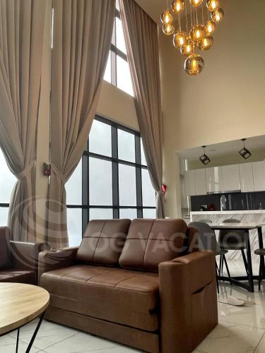 a living room with a brown couch and a table at Lovely 3-bedrooms with Karaoke Genting Penthouse in Genting Highlands