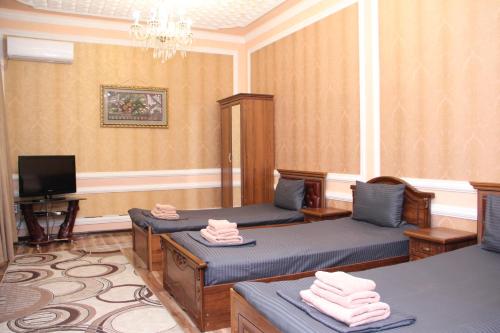 um quarto com duas camas e uma tv nele em BEST GUESTHOUSE em Tashkent