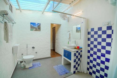 a bathroom with a toilet and a sink at SaffronStays The Lodge at Dalewal, Hoshiarpur in Hoshiārpur