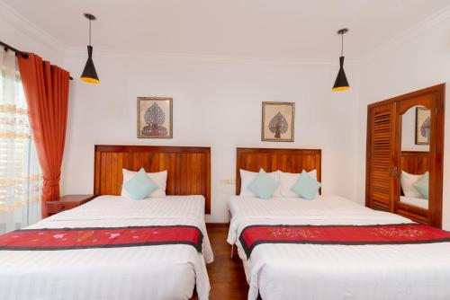 2 Betten in einem Zimmer mit weißen Wänden in der Unterkunft Asanak D'Angkor Boutique Hotel in Siem Reap