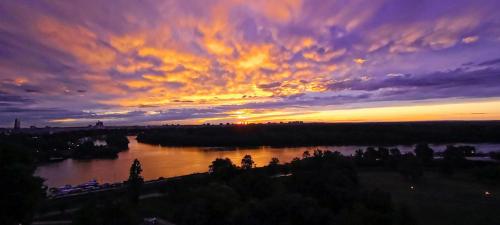 een zonsondergang boven een rivier met een bewolkte lucht bij Angelo S in Belgrado