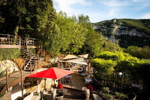 a patio with a red umbrella and tables and chairs at Le Belvedere in Vallon-Pont-dʼArc