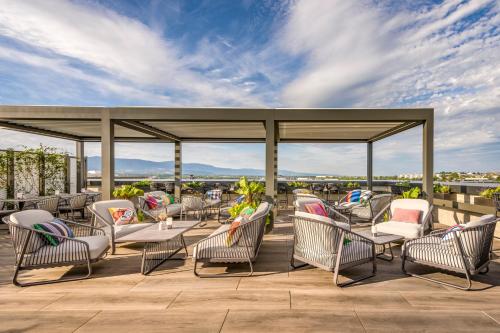 eine Terrasse mit Stühlen und Tischen auf dem Dach in der Unterkunft Geneva Marriott Hotel in Genf