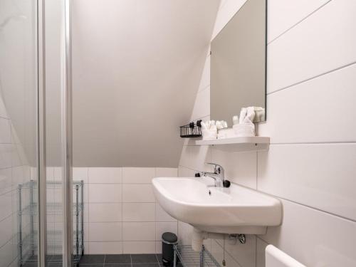 La salle de bains blanche est pourvue d'un lavabo et d'un miroir. dans l'établissement Modern renovated apartment in the heart of Sneek, à Sneek