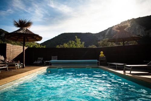 a swimming pool with a couch and an umbrella at Le Belvedere in Vallon-Pont-dʼArc