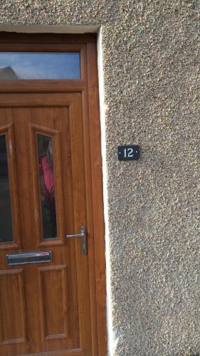 a wooden door with the number next to a building at 2 Bedroom Townhouse on NC500, Wick, Highland in Wick