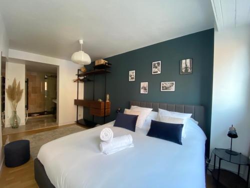 une chambre avec un grand lit blanc avec des murs bleus dans l'établissement L'Eclatant - Au cœur de Toulouse, à Toulouse