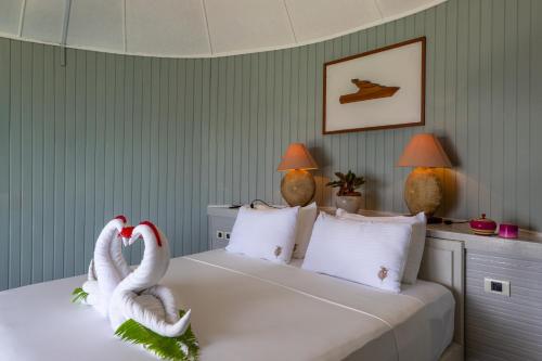 two swans sitting on a bed in a bedroom at Nika Island Resort & Spa, Maldives in Nika Island