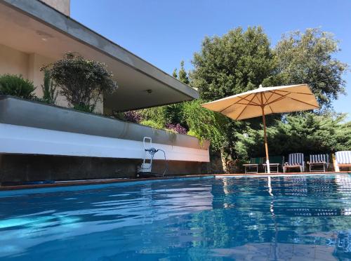 a swimming pool with an umbrella and chairs at Villa Marisa in Fregene