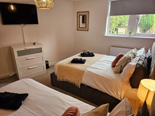 a bedroom with two beds and a tv on the wall at Homebird Property - Epsom Apartment in Harrogate