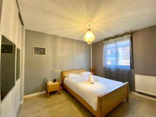 een slaapkamer met een bed met witte lakens en een raam bij La Garonne - T3 avec parking privé in Toulouse
