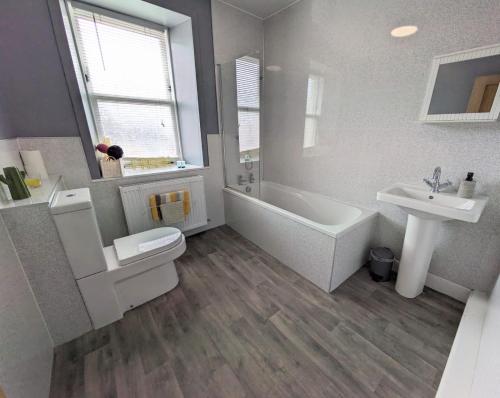 a bathroom with a tub and a toilet and a sink at 2 Bedroom Townhouse on NC500, Wick, Highland in Wick