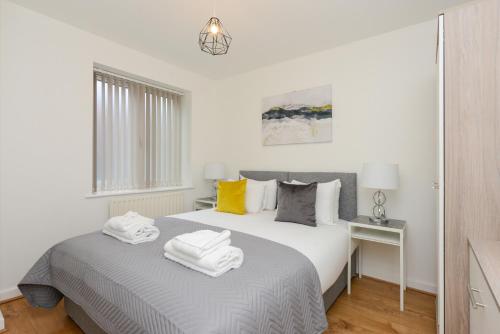 a white bedroom with a bed with towels on it at The Zone - Vibrant City Centre Apartment in Nottingham