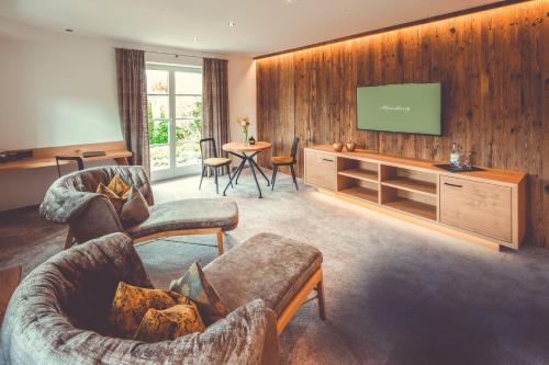 a living room with two couches and a flat screen tv at Hotel Alpenkönig in Oberstaufen