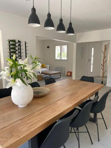 une grande table en bois avec des chaises et un vase avec des fleurs dans l'établissement Belle maison mitoyenne de standing, à Fréjus