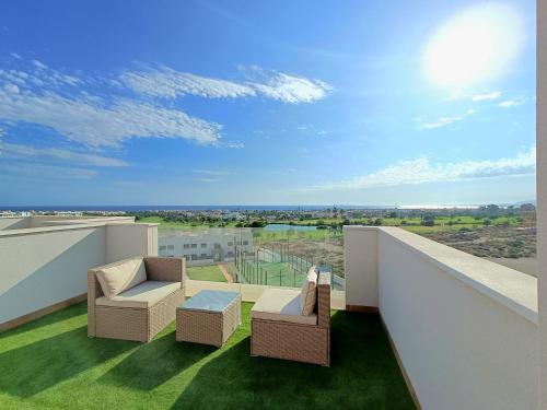 un balcone con 2 sedie e un tavolo su un edificio di Nuevo Ático Toyo. Vistas al mar, terraza, solarium, piscina, A/A, WiFi y Garaje a El Toyo