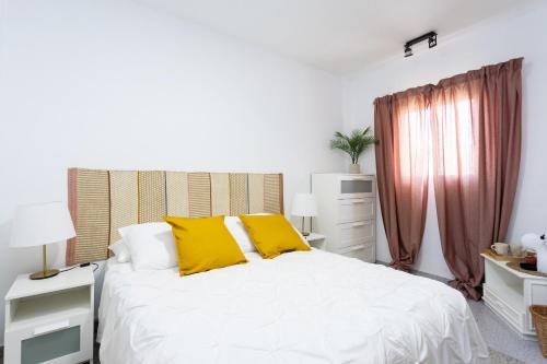 Una cama blanca con almohadas amarillas en un dormitorio en EDEN RENTALS 105 Surfy Stylish Bed&Coffee Room, en Granadilla de Abona