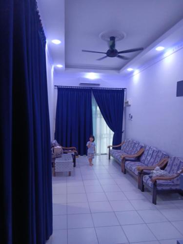 a little girl walking through a living room with blue curtains at Teratak Amani Hometay in Tawau