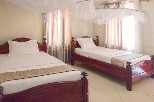 a bedroom with two beds and a window with curtains at G-ONE HOTEL in Kampala