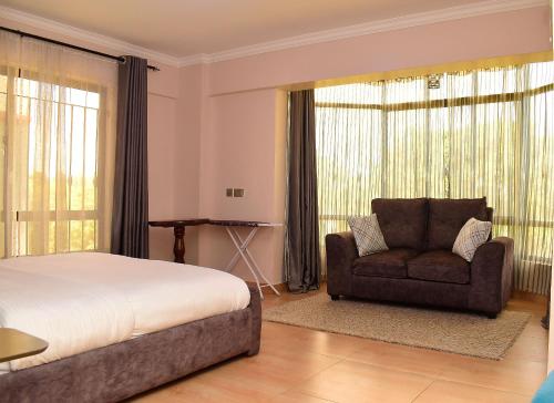 um quarto com uma cama, um sofá e uma cadeira em RAVIC HOMES NAKURU em Nakuru