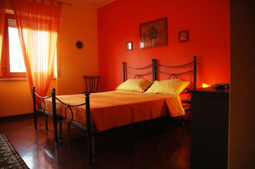 a bedroom with a bed with an orange wall at Liana Guest House in Alghero