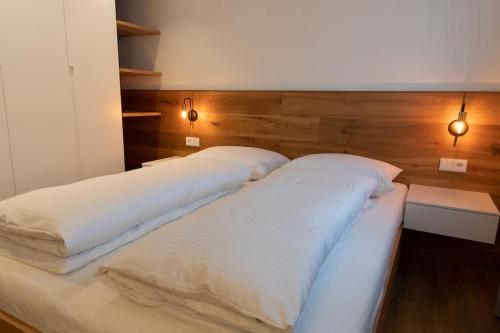 duas camas brancas num quarto com duas luzes em Appartement Sonnlicht em Falzes