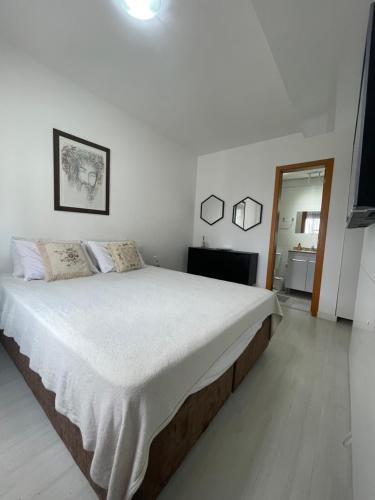a white bedroom with a large bed in it at Vista Panorâmica com piscina in Porto Alegre