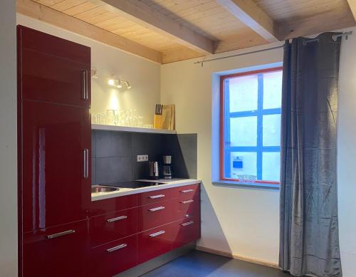 cocina con armario rojo y ventana en Himmel & Hölle Ferienhäuser en Quedlinburg