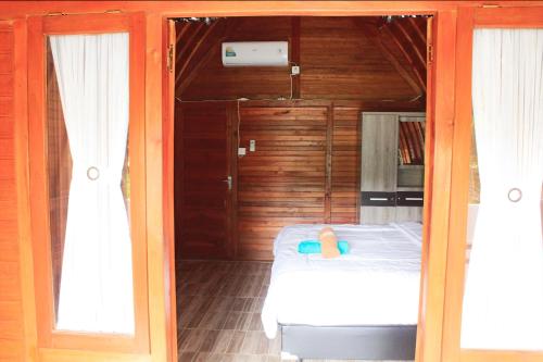 ein Schlafzimmer mit einem Bett und zwei Fenstern in der Unterkunft Sekar Kuning Cottage in Toyapakeh