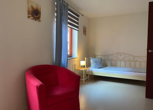 um quarto com uma cadeira vermelha e uma cama em Himmel & Hölle Ferienhäuser em Quedlinburg