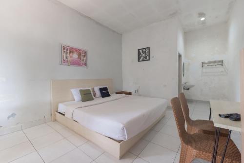 a white bedroom with a bed and a desk at Urbanview Hotel D'Pineapple Villa Ciater by RedDoorz in Subang