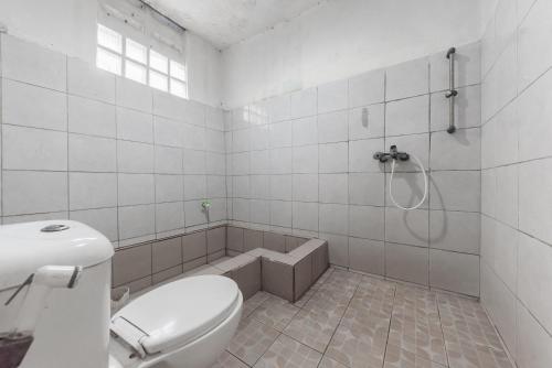 a white bathroom with a toilet and a shower at Urbanview Hotel D'Pineapple Villa Ciater in Subang