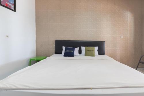 a bedroom with a white bed with three pillows at Urbanview Hotel D'Pineapple Villa Ciater by RedDoorz in Subang