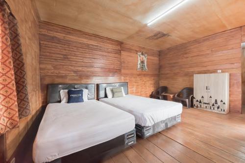 a bedroom with two beds in a room with wooden walls at Urbanview Hotel D'Pineapple Villa Ciater in Subang