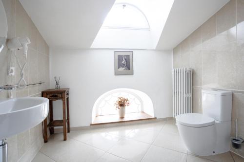 a white bathroom with a toilet and a sink at Burbiskio dvaras in Anykščiai