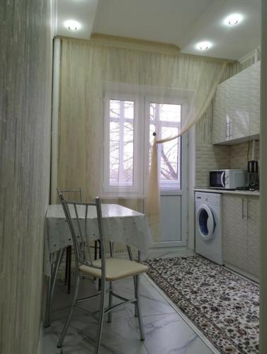 cocina con mesa, sillas y lavadora en Кылышбай акына en Taraz