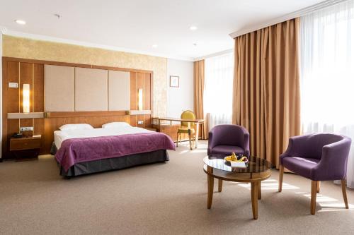a hotel room with a bed and a table and chairs at Reikartz Sky Almaty in Almaty