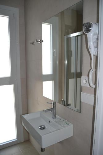 y baño con lavabo blanco y espejo. en Hotel OASIS CENTRO, en Conil de la Frontera