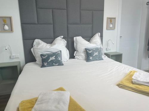 a large white bed with blue and white pillows at Jimmy's Place - Hotelgefühl, Tolle Lage, Terrasse, BBQ in Bad Zwischenahn