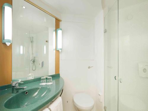 La salle de bains est pourvue d'un lavabo vert et de toilettes. dans l'établissement Ibis Madrid Alcorcon Tresaguas, à Alcorcón