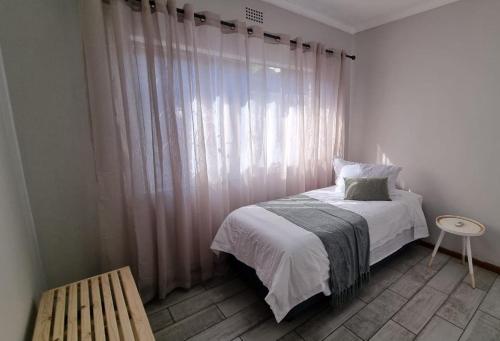 金伯利11 Debonair Self Catering Apartment的一间带床的卧室和一扇带窗帘的窗户
