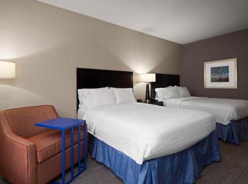 a hotel room with two beds and a chair at Hampton Inn & Suites Arundel Mills/Baltimore in Hanover