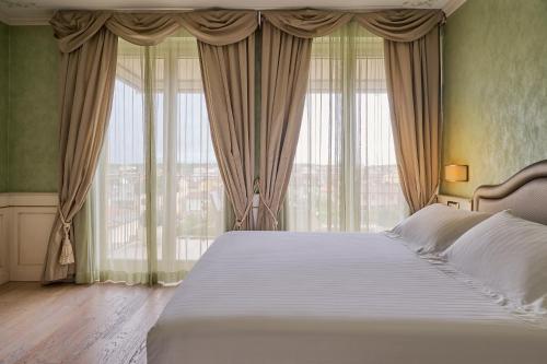ein Schlafzimmer mit einem großen Bett und großen Fenstern in der Unterkunft Grand Hotel Imperiale - Preferred Hotels & Resorts in Forte dei Marmi