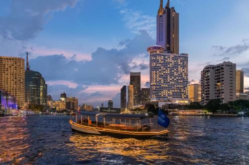 a boat on a river with a city in the background at Millennium Hilton Bangkok in Bangkok